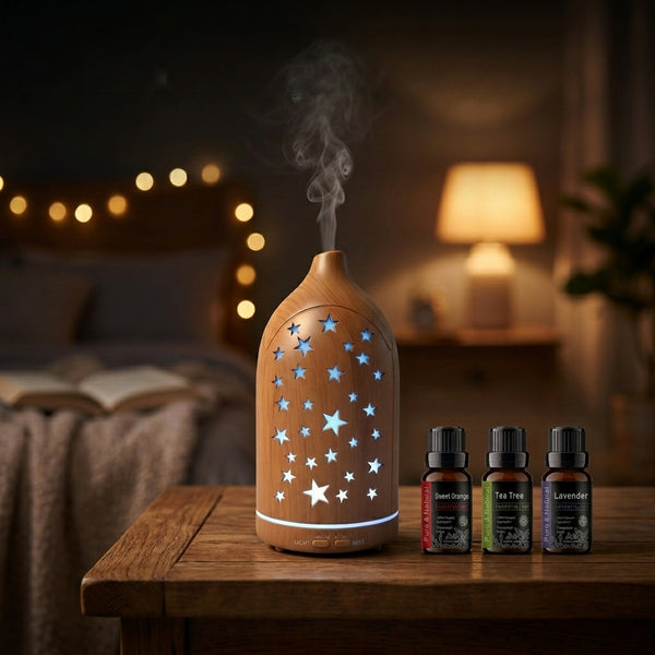 Light wood grain star cutout diffuser emitting blue LED light on a wooden nightstand in a cozy bedroom with fairy lights, accompanied by Sweet Orange, Tea Tree, and Lavender essential oils.