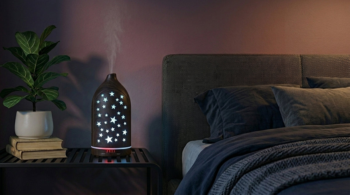 Dark wood grain star cutout diffuser emitting a calming sky blue starlight glow on a modern nightstand in a dimly lit bedroom, next to a fiddle leaf fig plant.