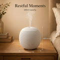 Restful Moments with the 100ml capacity white diffuser, showing actual product dimensions: 4.69 inch height and 4.45 inch width on a nightstand.