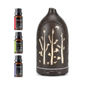 Front view of the dark wood grain forest cutout diffuser with control buttons (Light, Continuous, 1H, 2H, Mist) and the included 3 essential oil bottles.