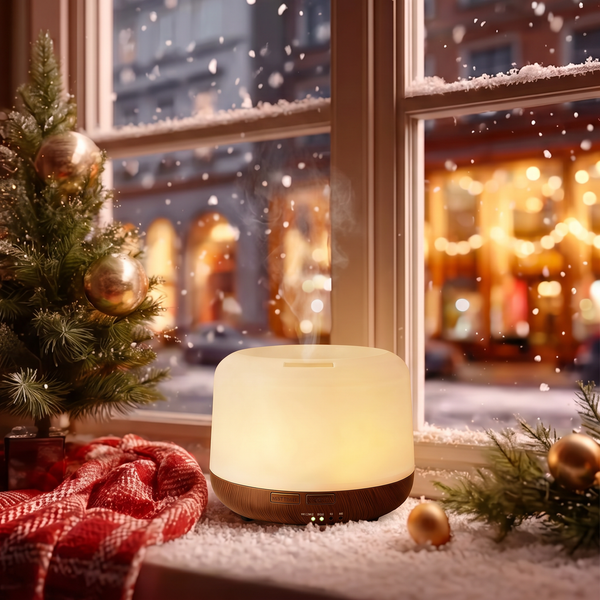 Mini dark wood diffuser glowing with warm light and mist on a snowy Christmas windowsill, decorated with a small Christmas tree, red plaid blanket, and gold ornaments, perfect for cozy winter holiday home ambience.