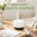 Hand holding the remote control for the Pniaw 500ml wood grain diffuser, demonstrating easy wireless operation from the sofa or bed.