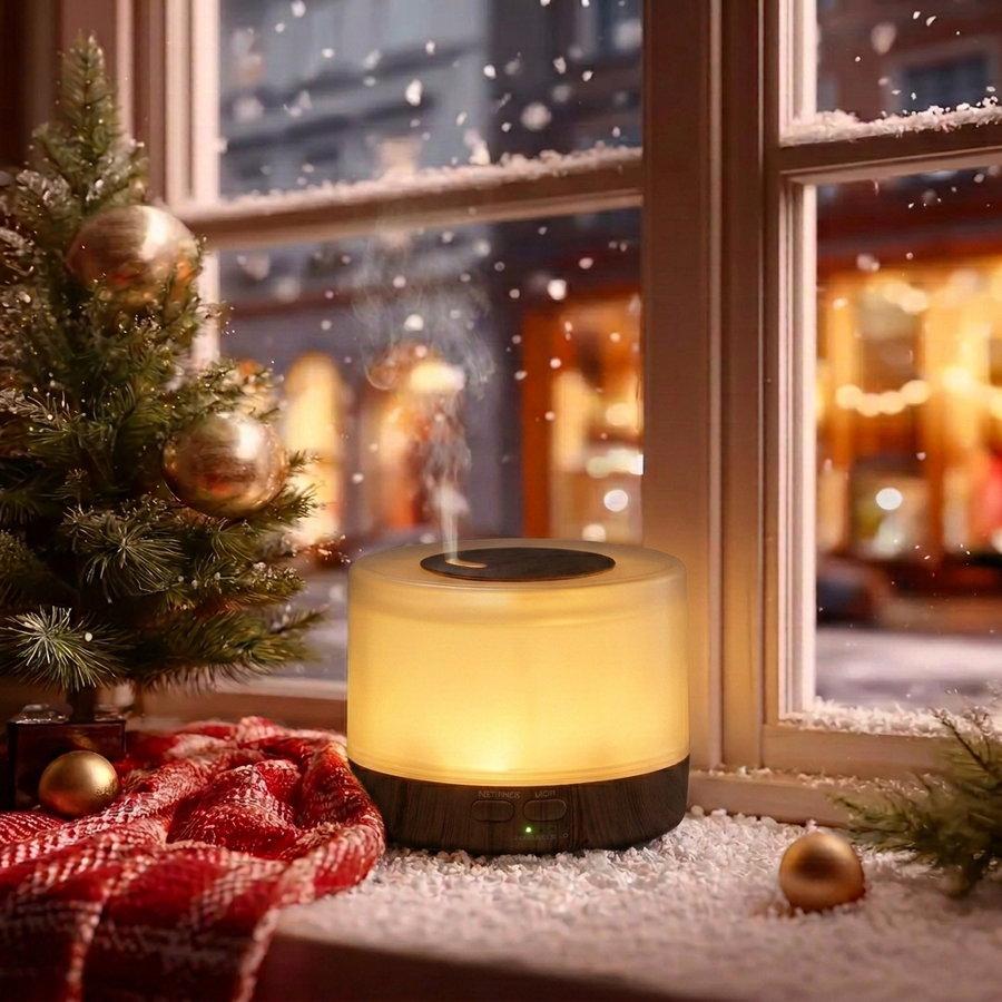 Round dark wood ultrasonic aromatherapy diffuser glowing with warm light and mist on a snowy Christmas windowsill, decorated with a small Christmas tree, red plaid blanket, and gold ornaments, creating a cozy winter holiday home ambience and ideal Christmas gift.