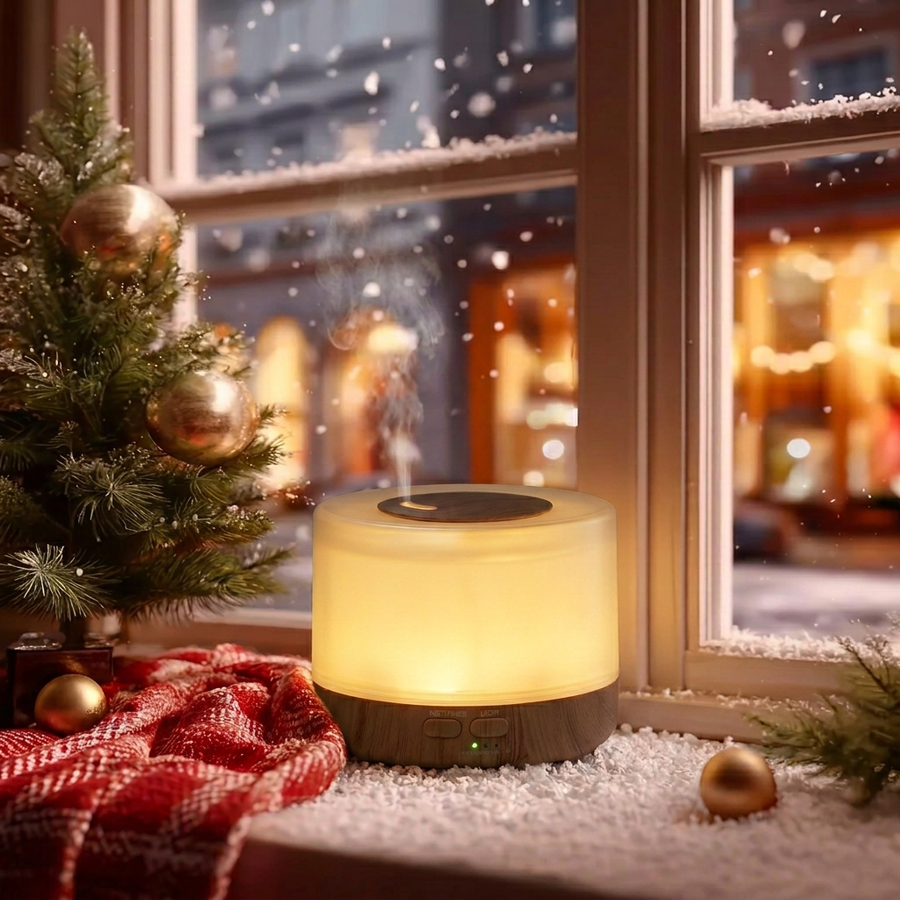 Round light wood ultrasonic aromatherapy diffuser glowing with warm light and mist on a snowy Christmas windowsill, decorated with a small Christmas tree, red plaid blanket, and gold ornaments, creating a cozy winter holiday home ambience and ideal Christmas gift.