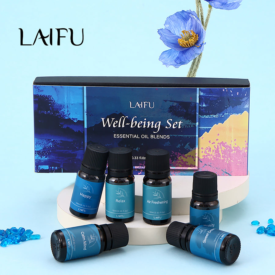 Well-being essential oil blends gift set displayed on a white pedestal with a blue flower decoration, perfect for gifting.
